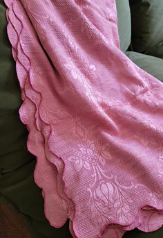 a pink blanket sitting on top of a green couch