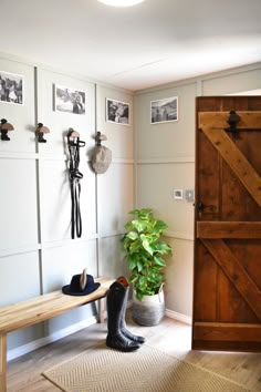 a wooden bench sitting in front of a door next to a potted plant on top of a rug