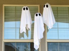 two ghost decorations hanging from the side of a window