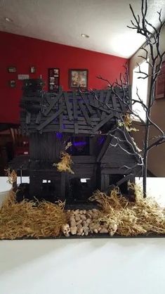 a fake house made out of wood and hay with a tree in the middle on top