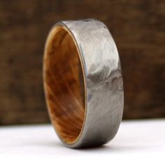 a wooden and metal wedding ring on a white surface with wood in the background,