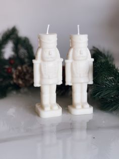 two white candles sitting on top of a table