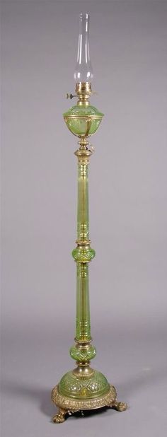 a green glass candle holder with a gold stand on the bottom and an ornate design around it