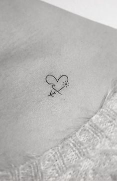 a small heart with an arrow tattoo on the side of a woman's stomach