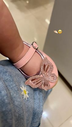 a small child's pink shoe with a butterfly decoration on it