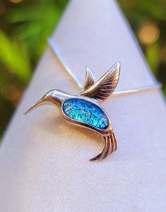 a close up of a bird brooch on a napkin with a tree in the background