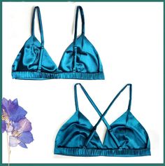 two blue bras with straps on them and a purple flower next to it in front of a white background