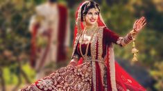 a woman in a red and gold bridal gown is holding her hands out to the side