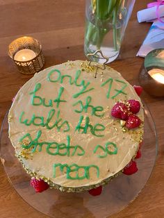 a cake with writing on it sitting on top of a wooden table next to candles