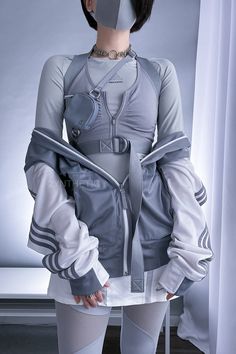 A person with short black hair is standing and wearing an all grey techwear outfit, with a white and grey Adidas track jacket. Cool Techwear Outfits, Feminine Cyberpunk Outfit, Future Aesthetic Outfit, Blue Techwear Outfit, Outfit Ideas Futuristic, Cyberpunk Outfit Inspiration, Rococo Techwear, Futuristic Casual Fashion, Korean Futuristic Fashion