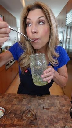 a woman holding a spoon in her mouth while eating something out of a mason jar