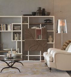 a living room filled with furniture next to a wall mounted book shelf and lamp on top of a rug