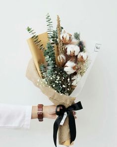 a person holding a bouquet of flowers in their left hand and wrapped in burlap