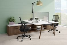 an office desk with two chairs and a computer monitor on top of it, in front of a large window