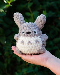 a hand holding a small crocheted toy with an animal on it's face