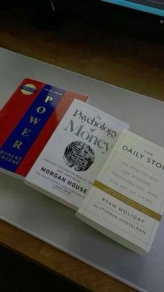 three books are sitting on top of a glass table in front of a computer screen