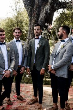 three men wearing suits and bow ties standing next to each other in front of a tree