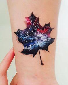 a woman's wrist tattoo with a colorful maple leaf on it