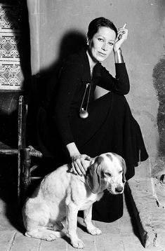 a black and white photo of a woman sitting next to a dog