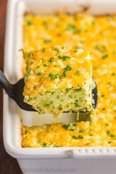 a casserole dish with broccoli and cheese being lifted by a spatula