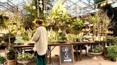 a woman standing in front of a table filled with plants