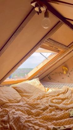 the bed is made and has yellow sheets on it, with an open window in the background