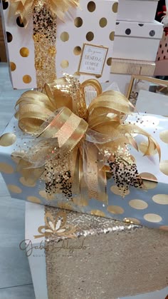 a gift wrapped in gold foil with a bow on it's top and some confetti sprinkles next to it