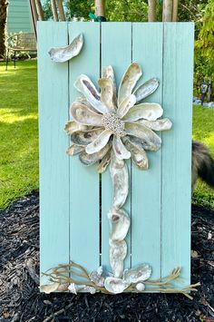 a wooden sign with shells and flowers on it