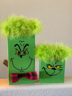 two green bags with faces painted on them, one has a bow tie and the other has a pair of yellow eyes