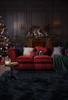 a living room decorated for christmas with a red couch and black rug on the floor