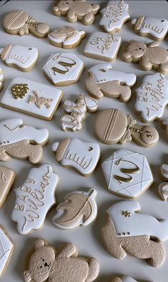 many decorated cookies are on a white tablecloth with gold trimmings and teddy bears