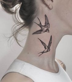 a woman's neck with two birds tattoo on her left side ribcage