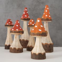 small wooden mushrooms with polka dots on them are lined up against a gray background,