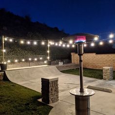 an empty skateboard park at night with lights strung over the top and around it