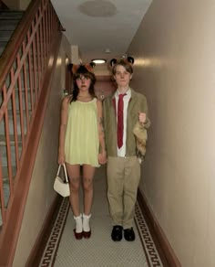 two people in costumes are standing on the hallway way, one is holding a teddy bear