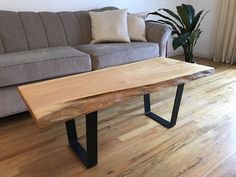 a wooden table sitting in front of a couch on top of a hard wood floor