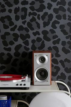 a record player sitting on top of a white table next to a wall with leopard print