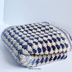 two blue and white crocheted cushions sitting next to each other