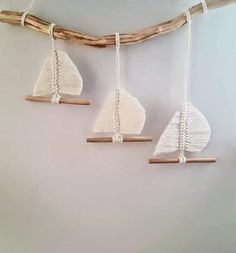 three white sailboats hanging from wooden sticks