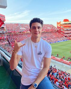 a man sitting in the bleachers at a soccer game with his finger up