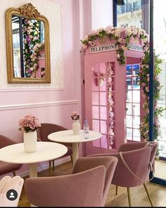 the interior of a restaurant with pink walls and chairs, tables, and a phone booth