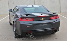 the back end of a gray chevrolet camaro parked in a parking lot next to a concrete wall