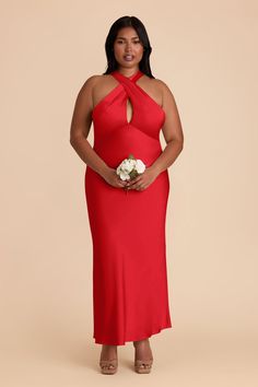 a woman in a red dress holding a white flower and standing against a beige background