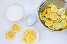 lemons and other ingredients are in bowls on a white counter top, including sugar