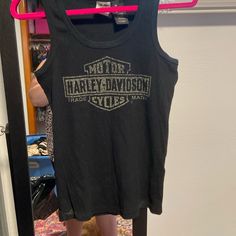 a black harley davidson tank top hanging on a pink hanger in front of a door