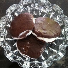 two chocolate cookies with white frosting on a glass plate