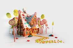 a gingerbread house surrounded by candy canes and lollipops on a white background