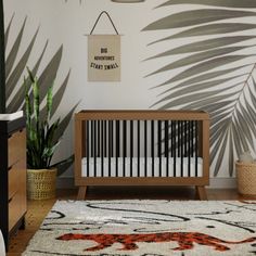 a baby crib in the corner of a room with palm leaves on the wall