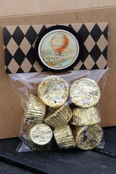 there is a bag full of gold foiled cookies in front of a box with an ornament on it