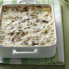 a casserole dish with meat and cheese in it on a green and white towel